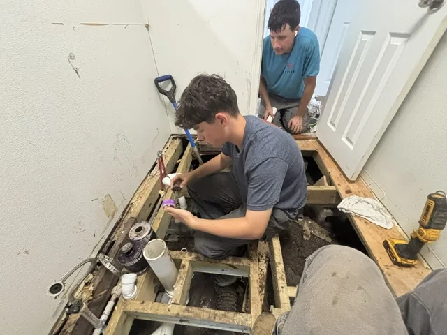 Titan Plumbing technicians repairing residential plumbing beneath a floor in Durant Oklahoma