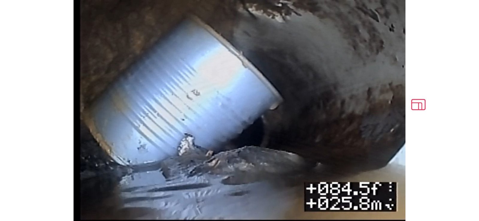 Sewer camera view showing a food can lodged inside the drain line.